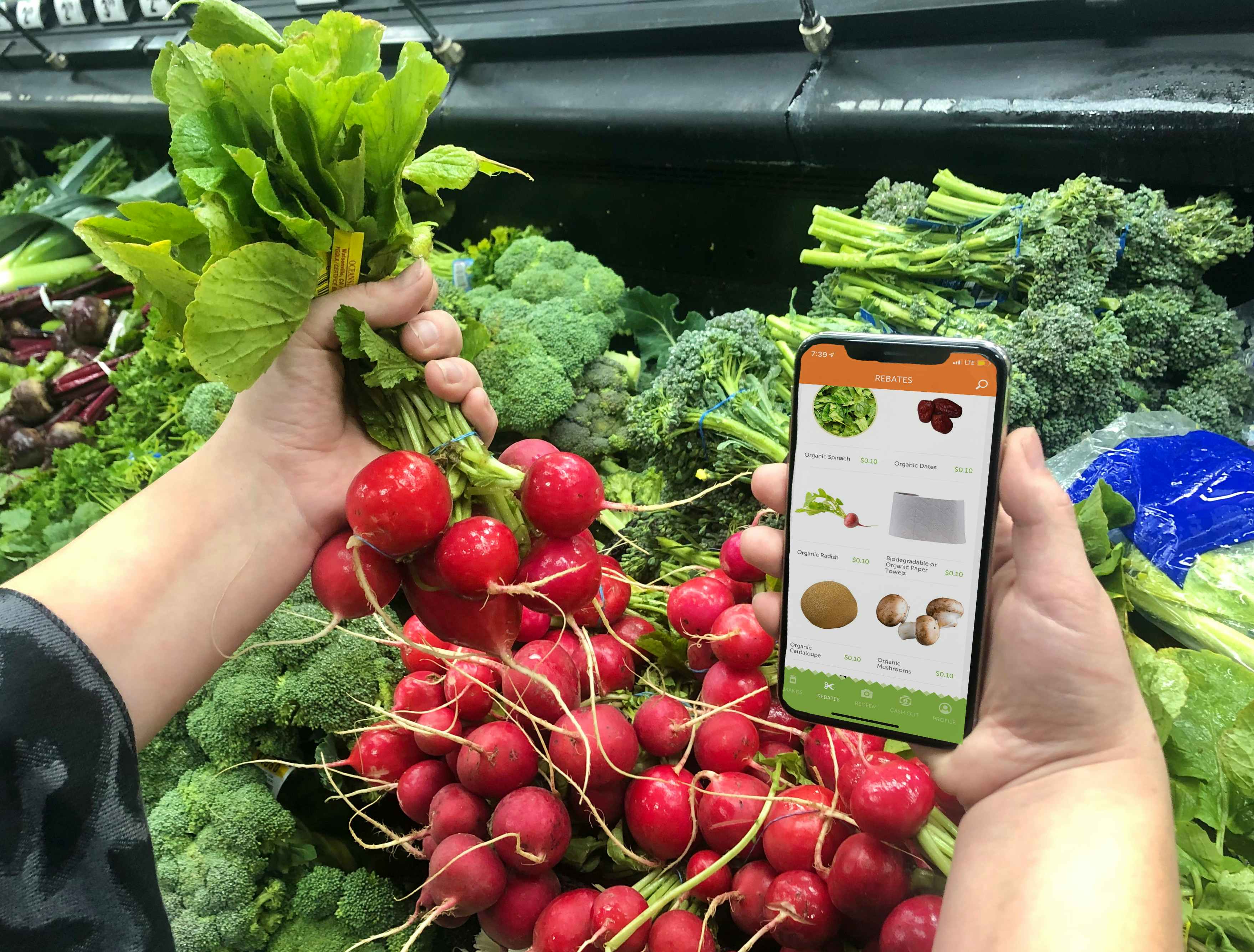 A woman holding a phone with the Makeena app in one hand and radishes in the other.