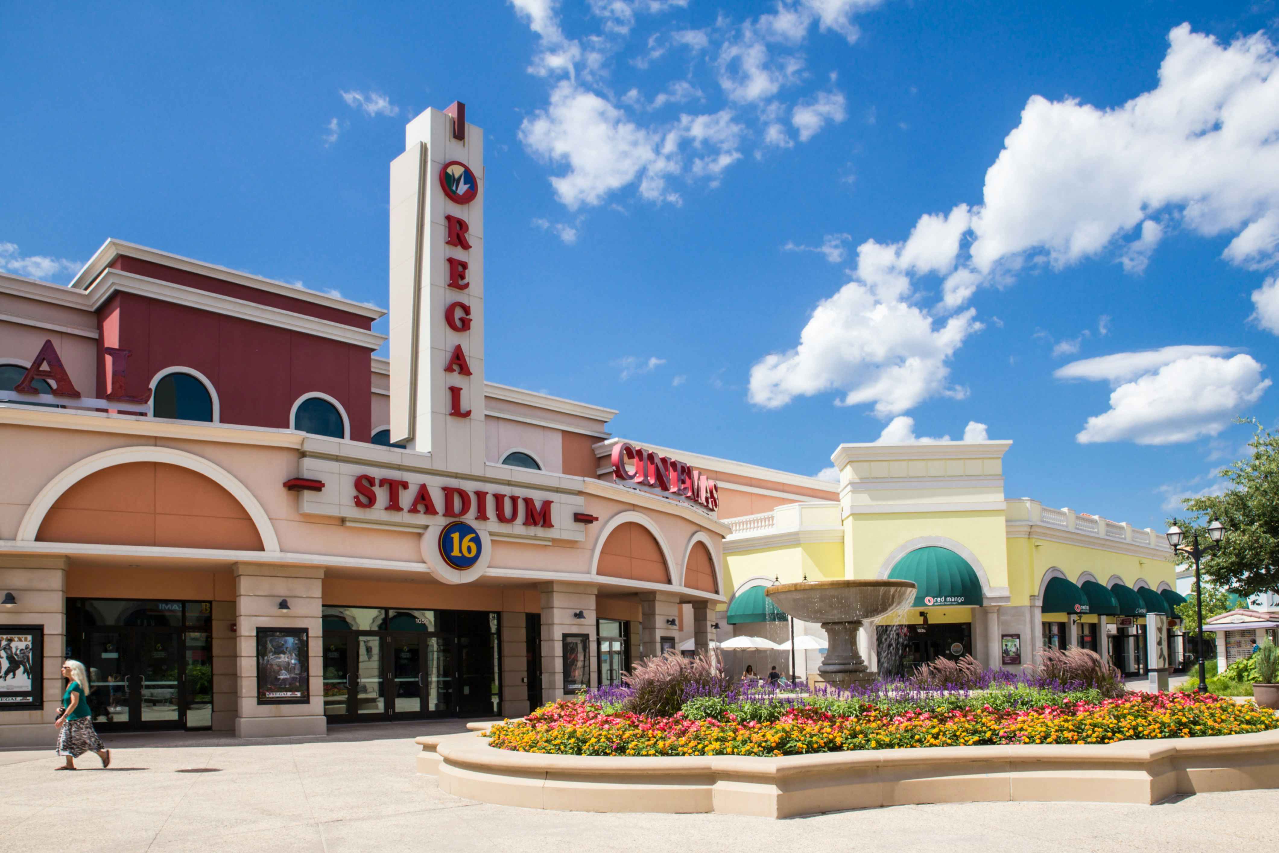 Outside view of Regal theater with a picturesque water fountain and flowers 
