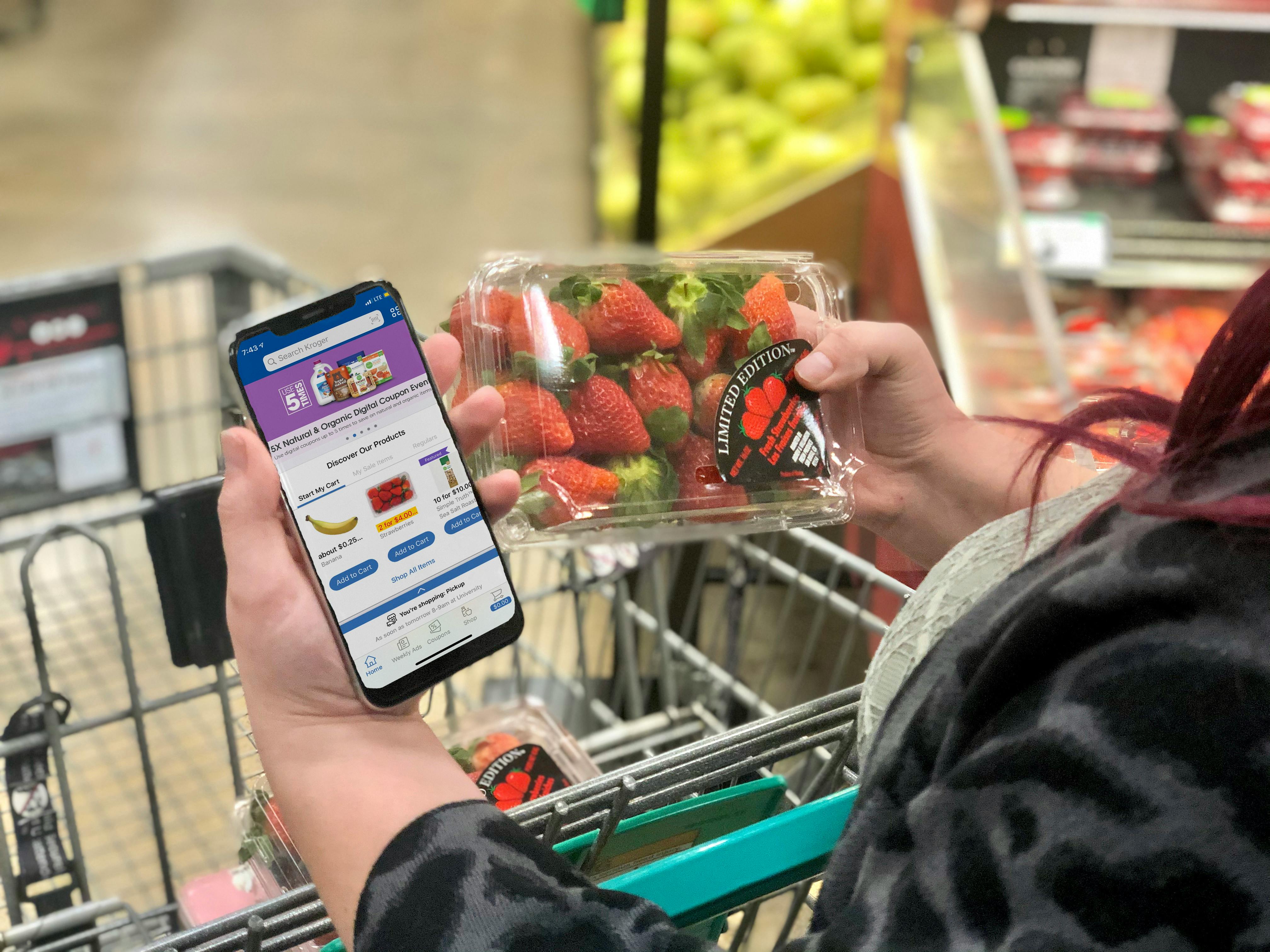 A woman has the Kroger app on her phone while shopping.