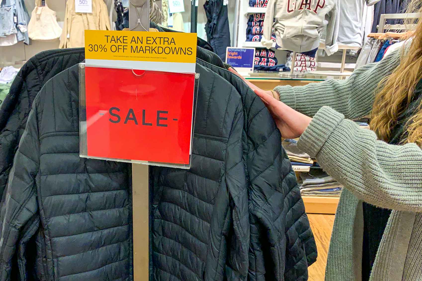 A person shopping for winter coats at GAP