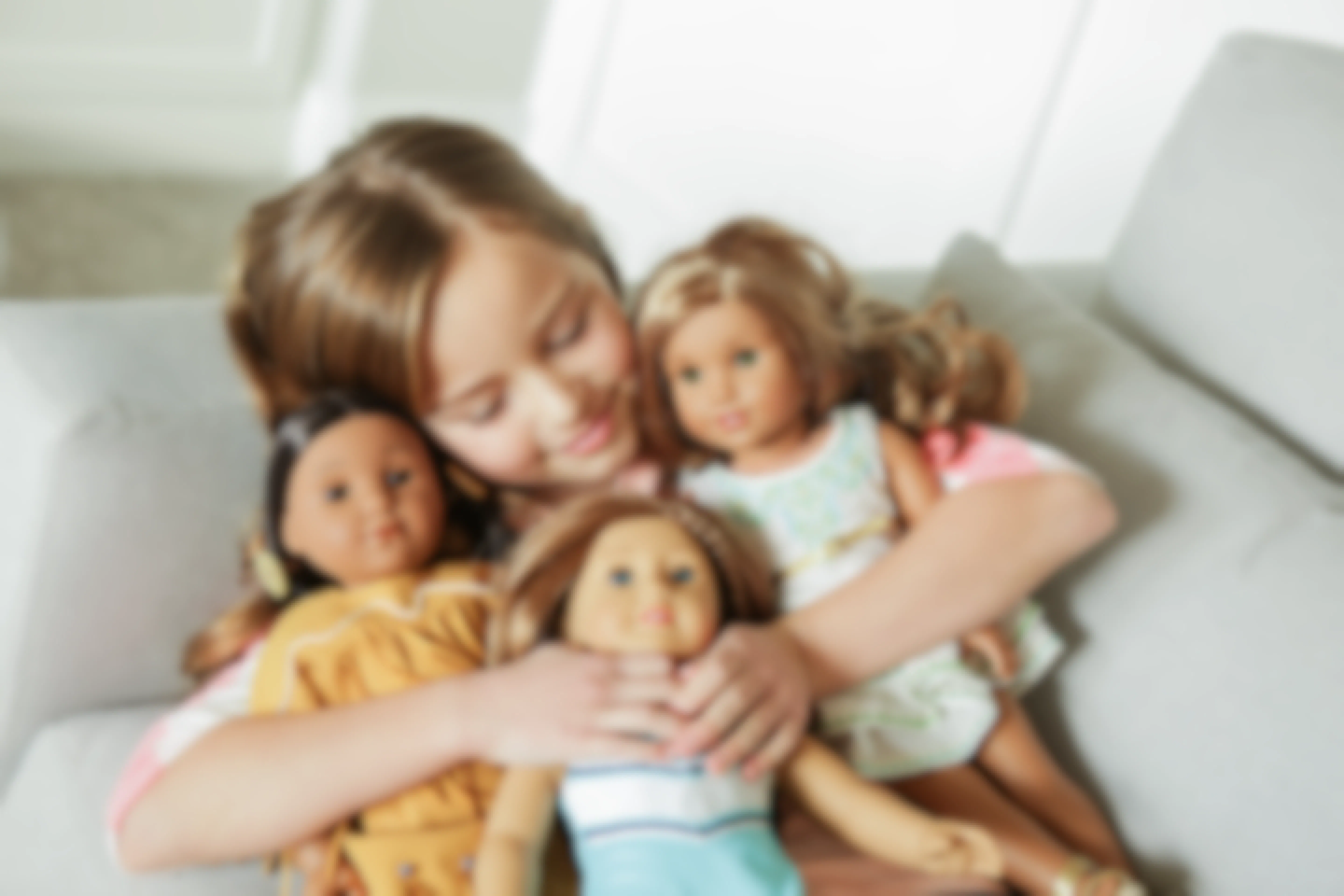 A girl cuddles her American Girl dolls