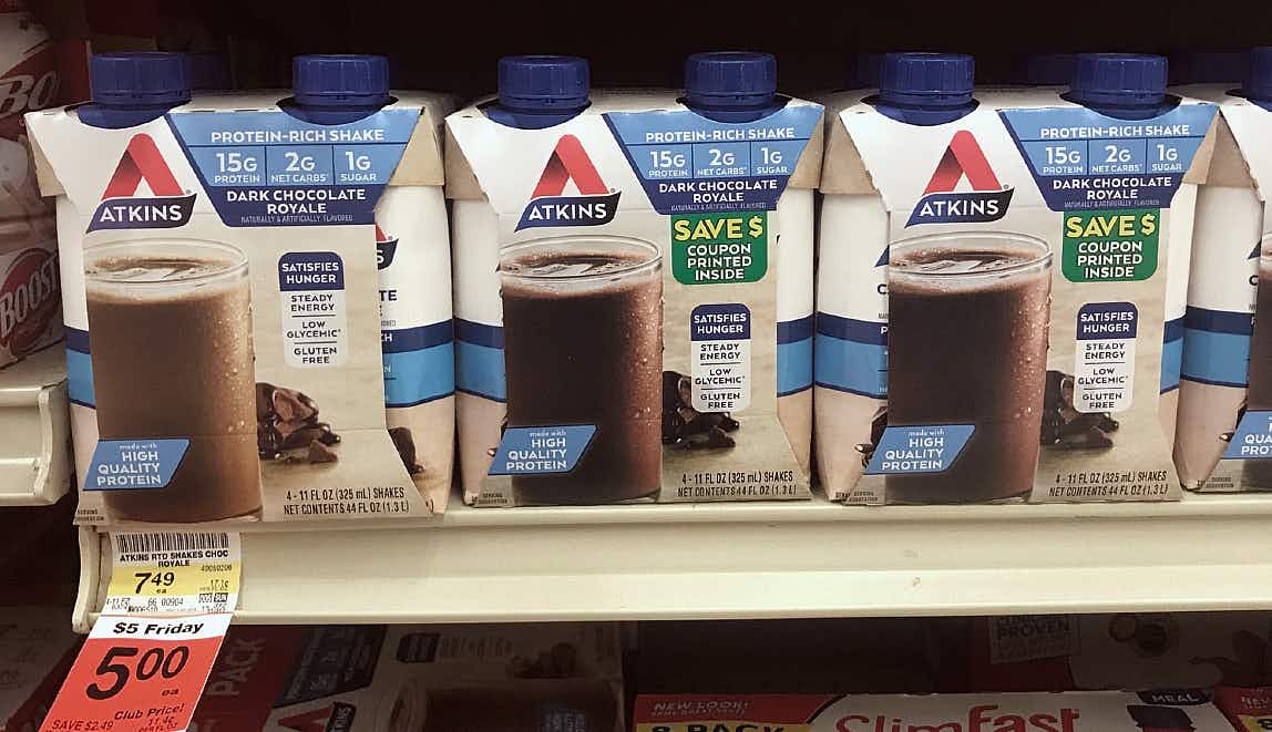 A shelf with Atkins chocolate drinks in a box with a label that read coupon printed inside.