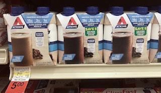 A shelf with Atkins chocolate drinks in a box with a label that read coupon printed inside.