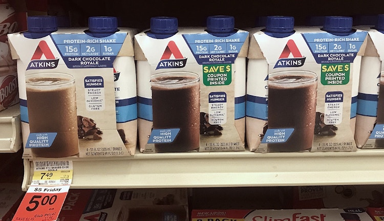 A shelf with Atkins chocolate drinks in a box with a label that read coupon printed inside.