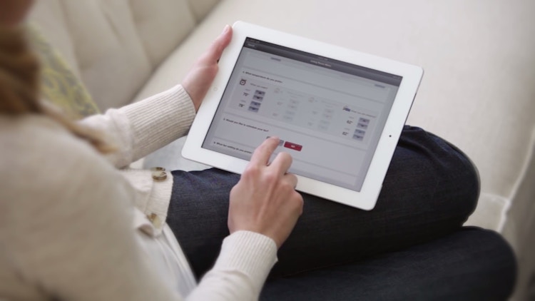 A person adjusting their thermostat settings using a tablet.
