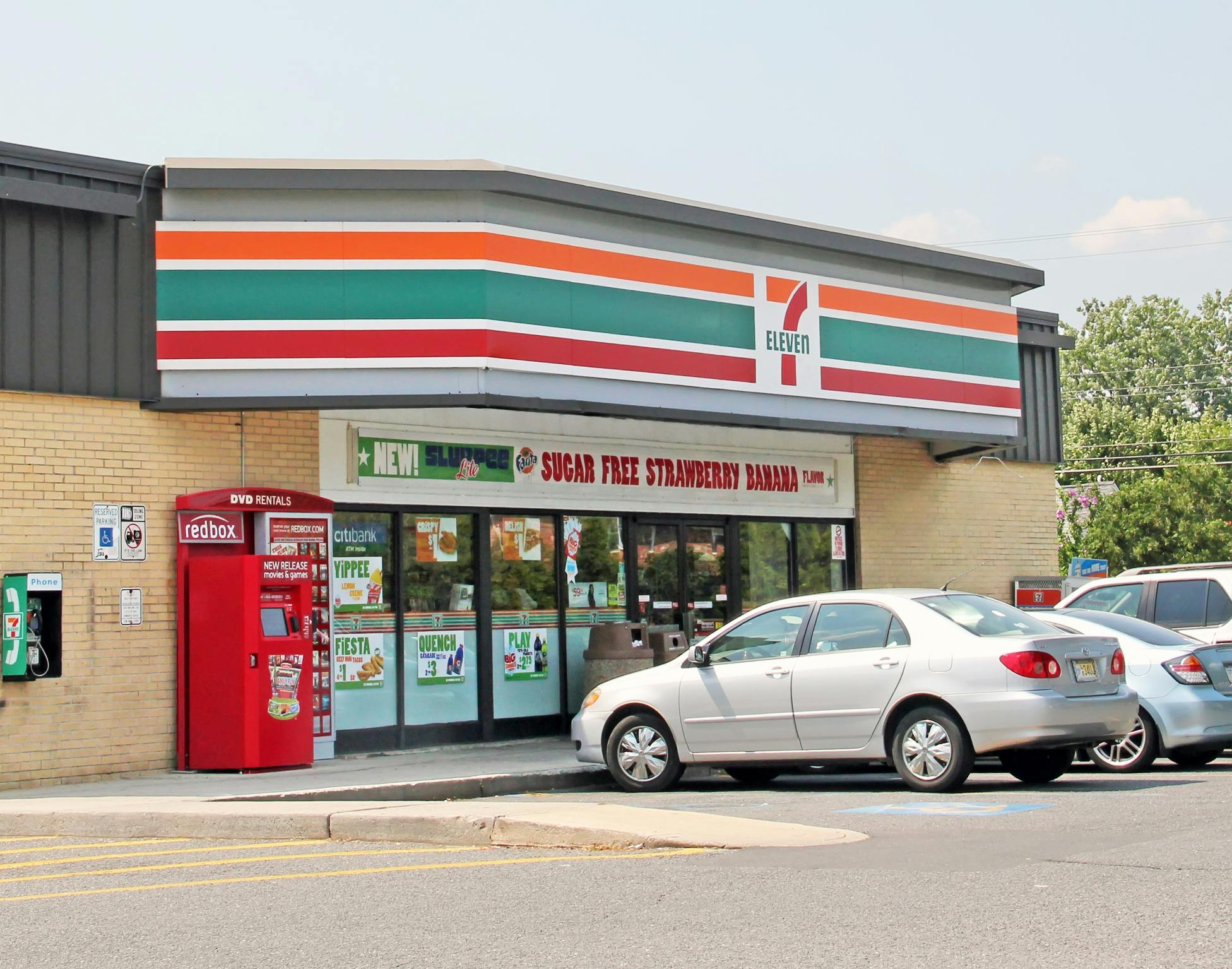A 7-eleven storefront with cars parked in front.