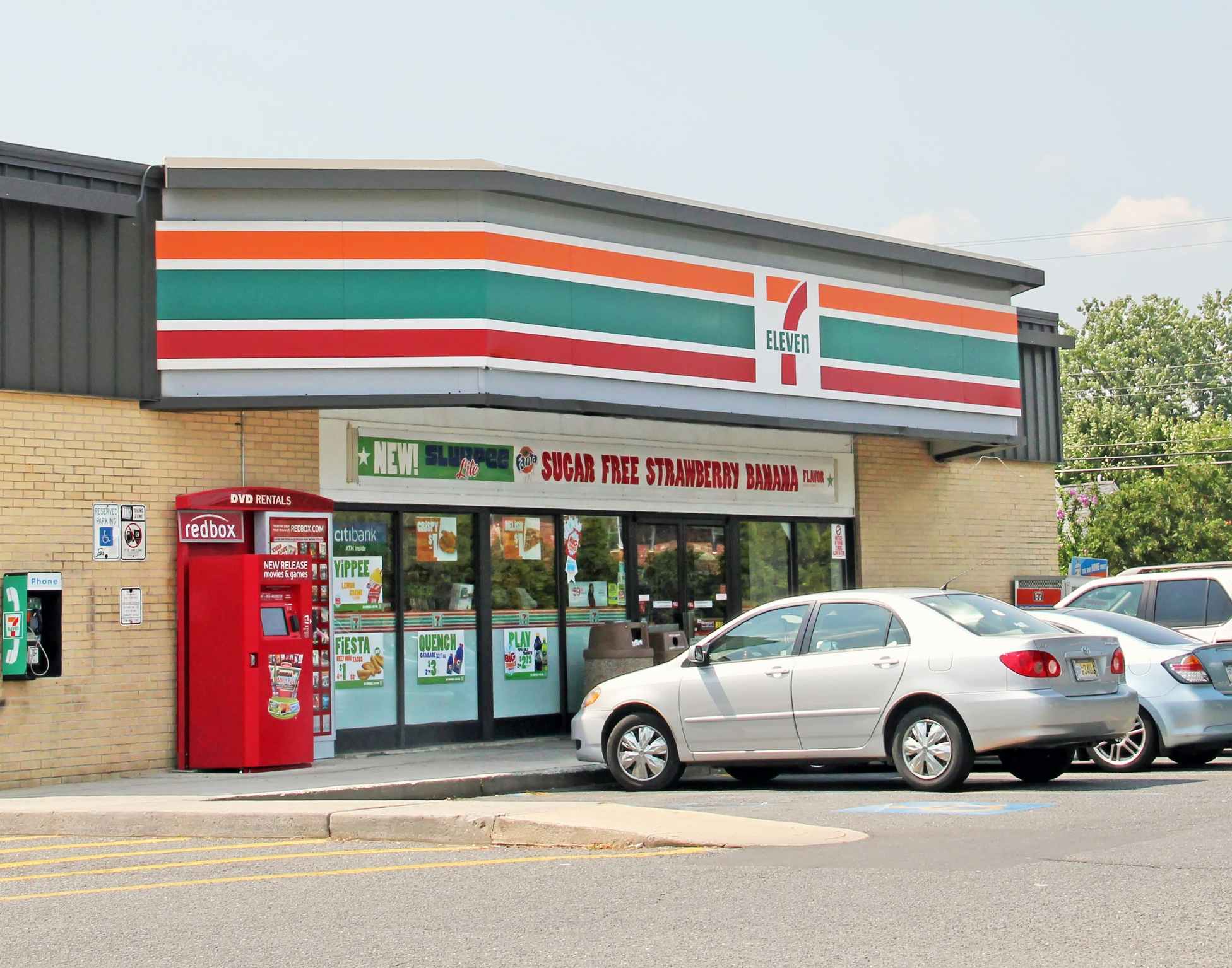 A 7-eleven store with cars parked in front.