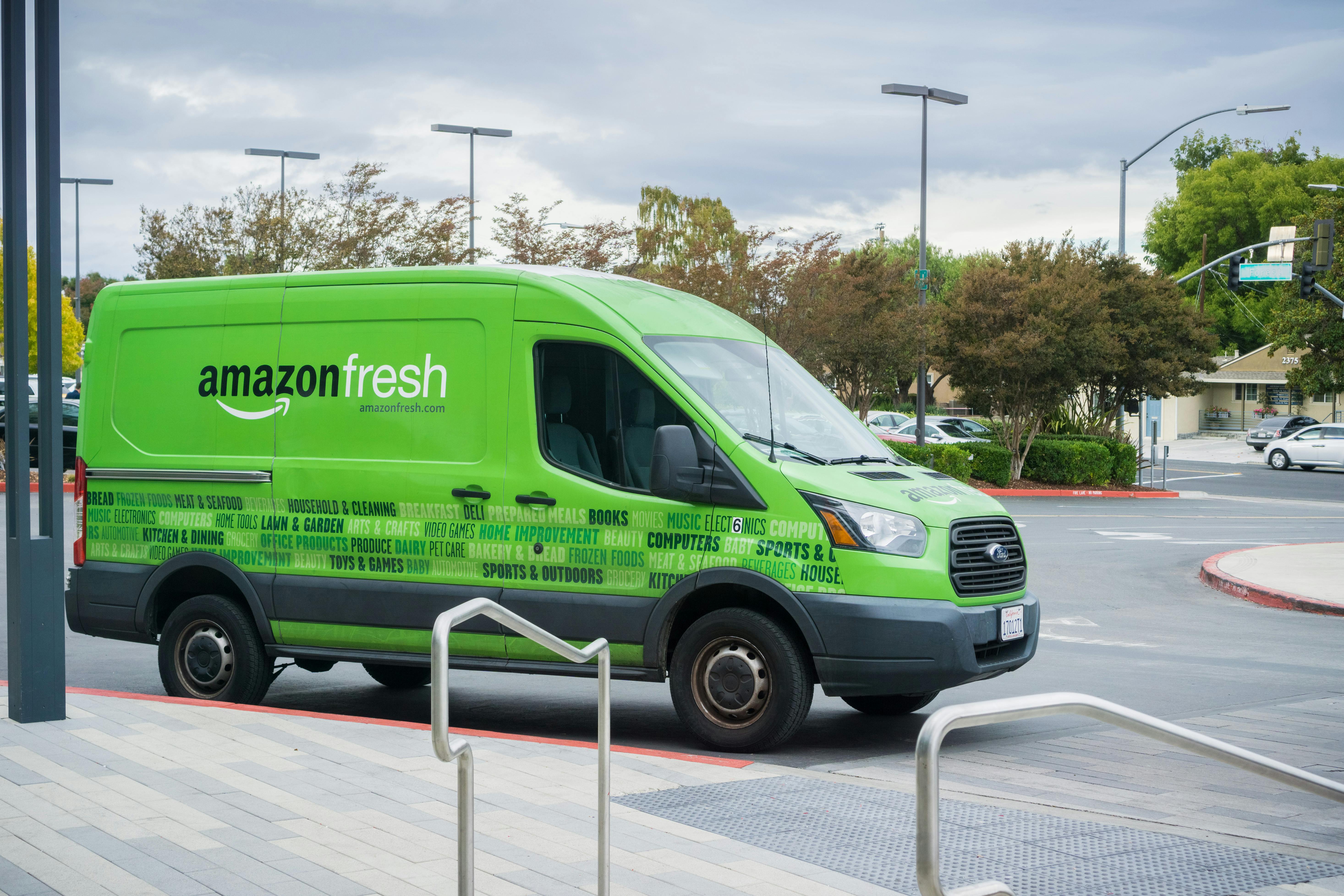 A green amazon fresh delivery truck parked in a parking lot.