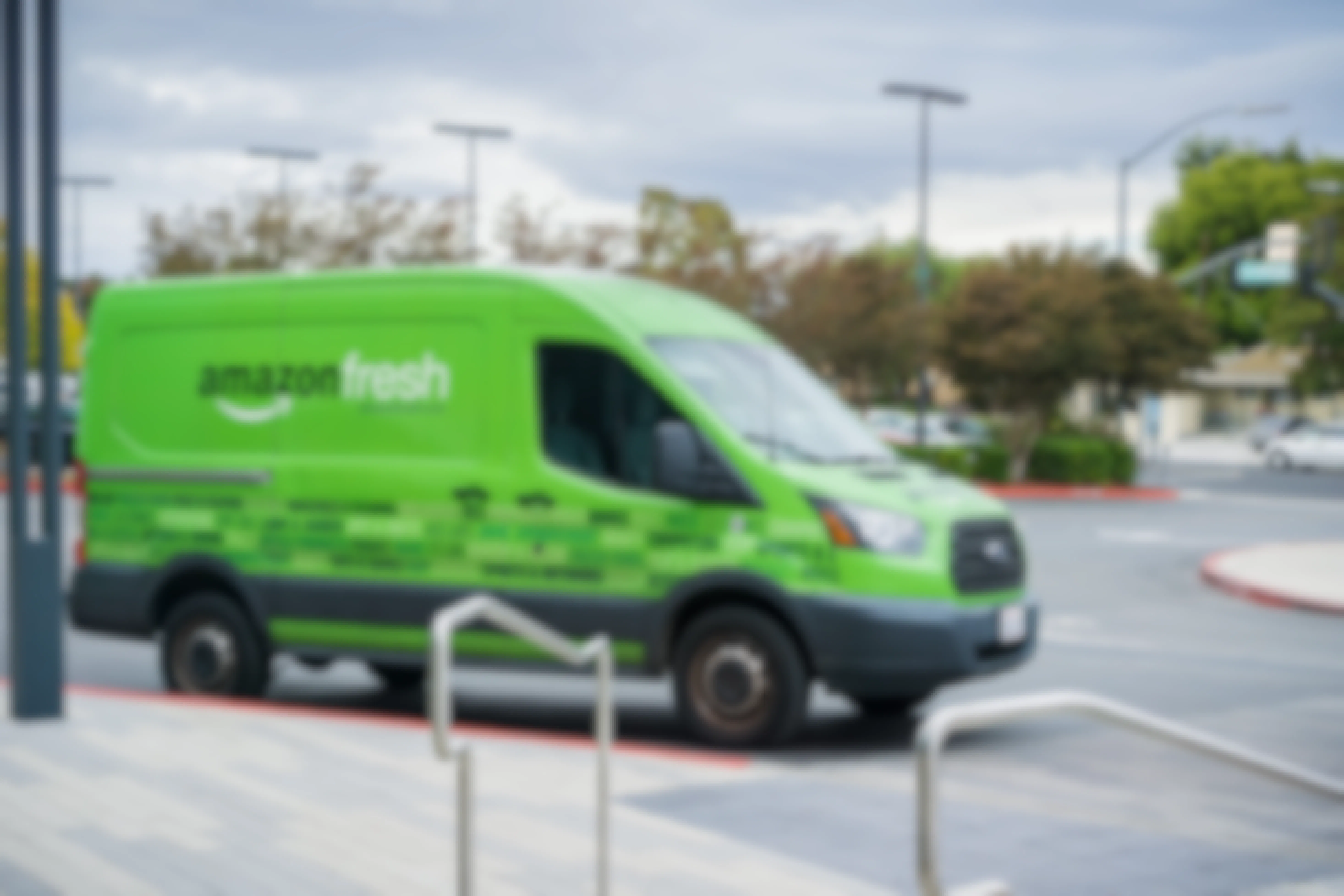 A green amazon fresh delivery truck parked in a parking lot.
