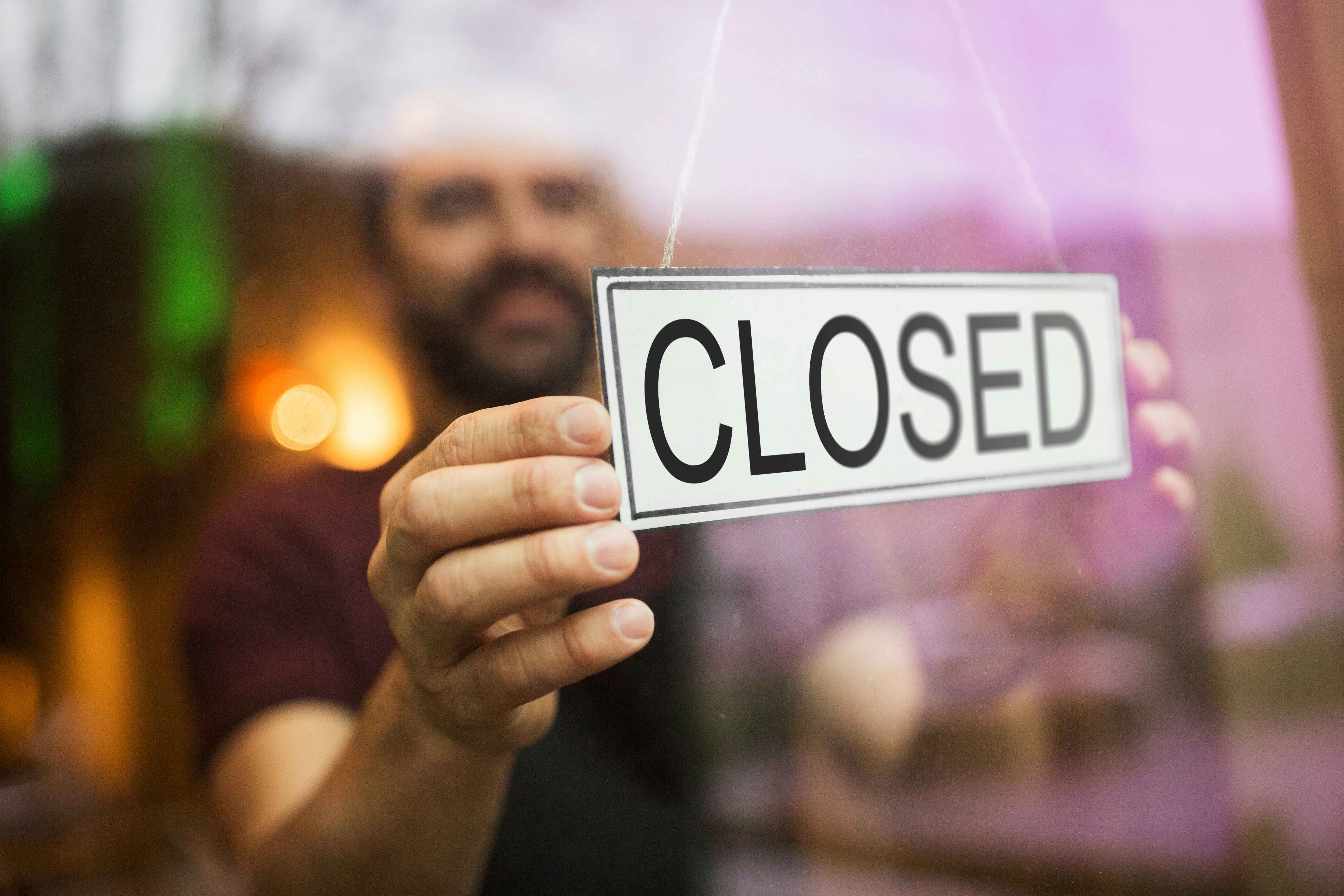 A man putting a closed sign up in a window.