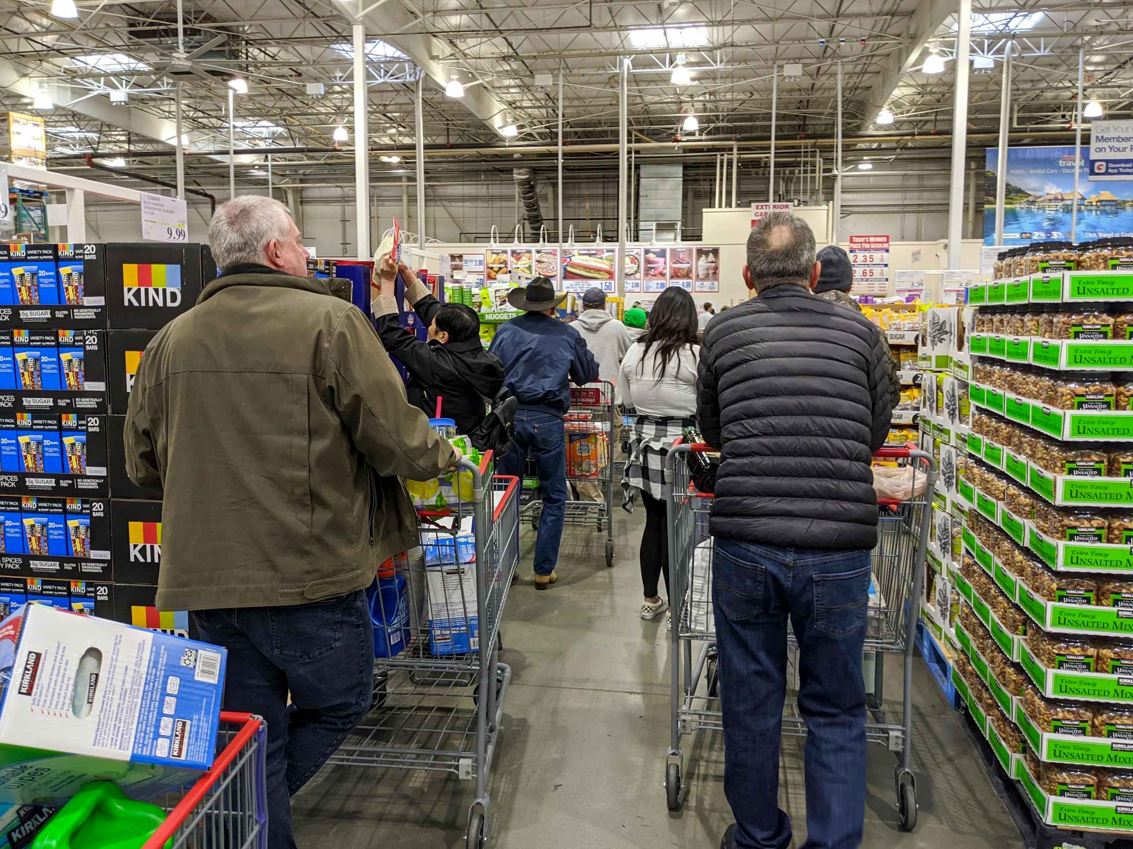Customers with baskets full of food standing in a long line at Costco checkout.
