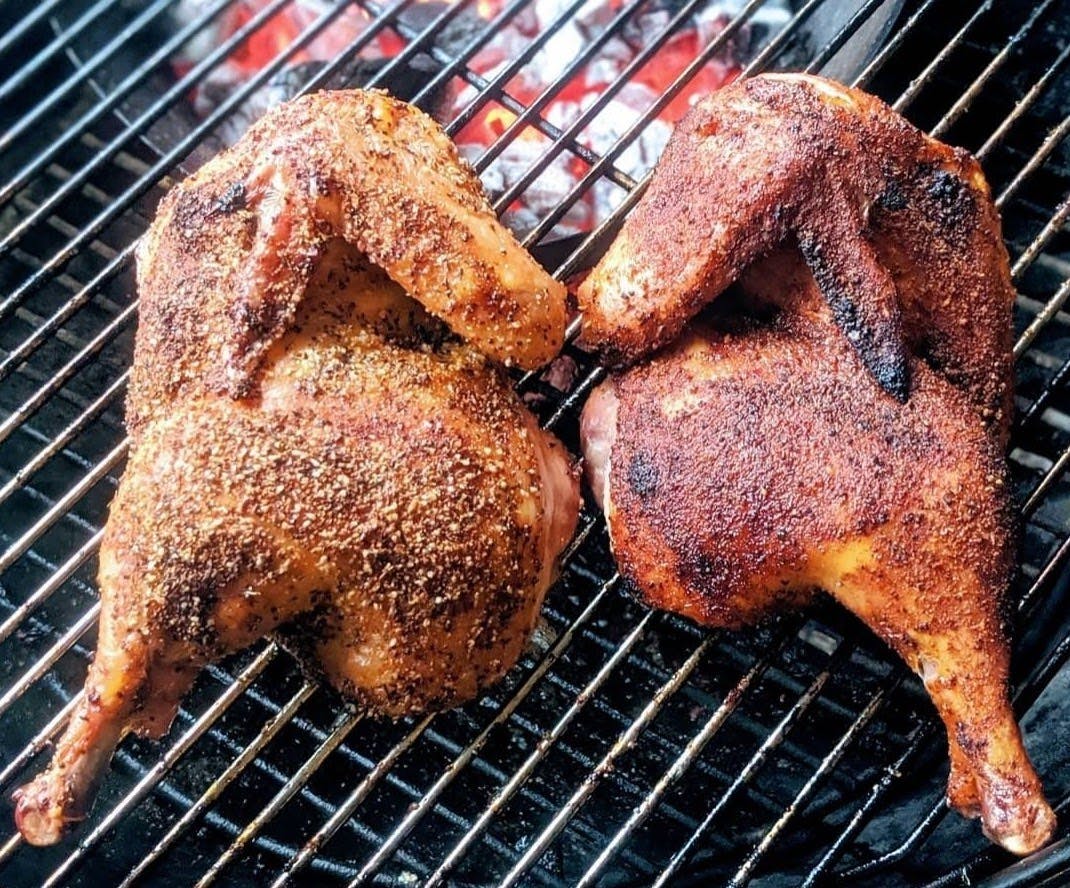 Chicken wings and thighs on a charcoal grill.