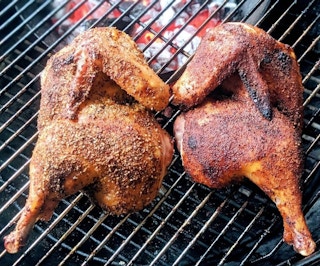 Chicken wings and thighs on a charcoal grill.
