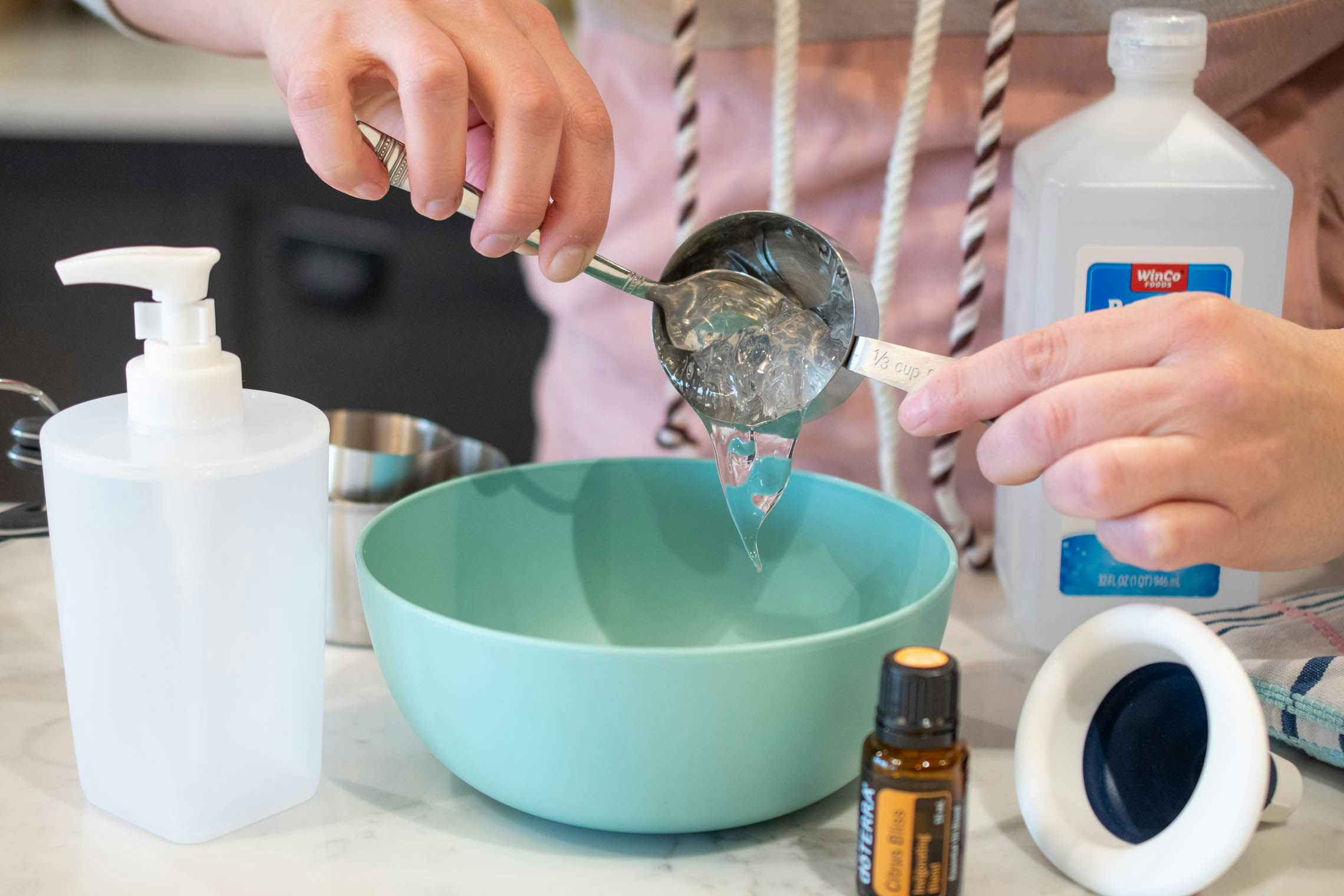 woman scooping out aloe vera gel into a bowl for homemade hand sanitizer