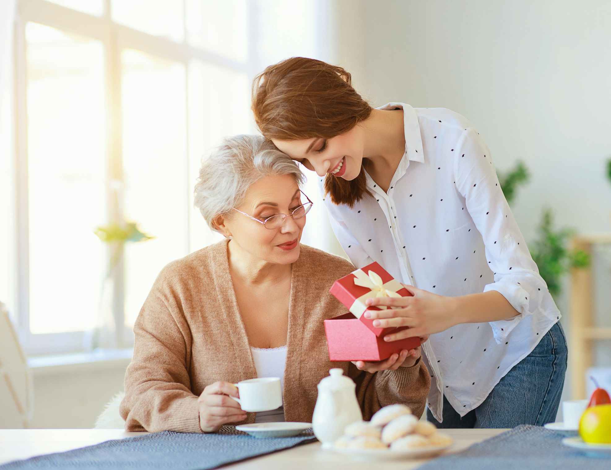 Young female opening a gift for elderly female