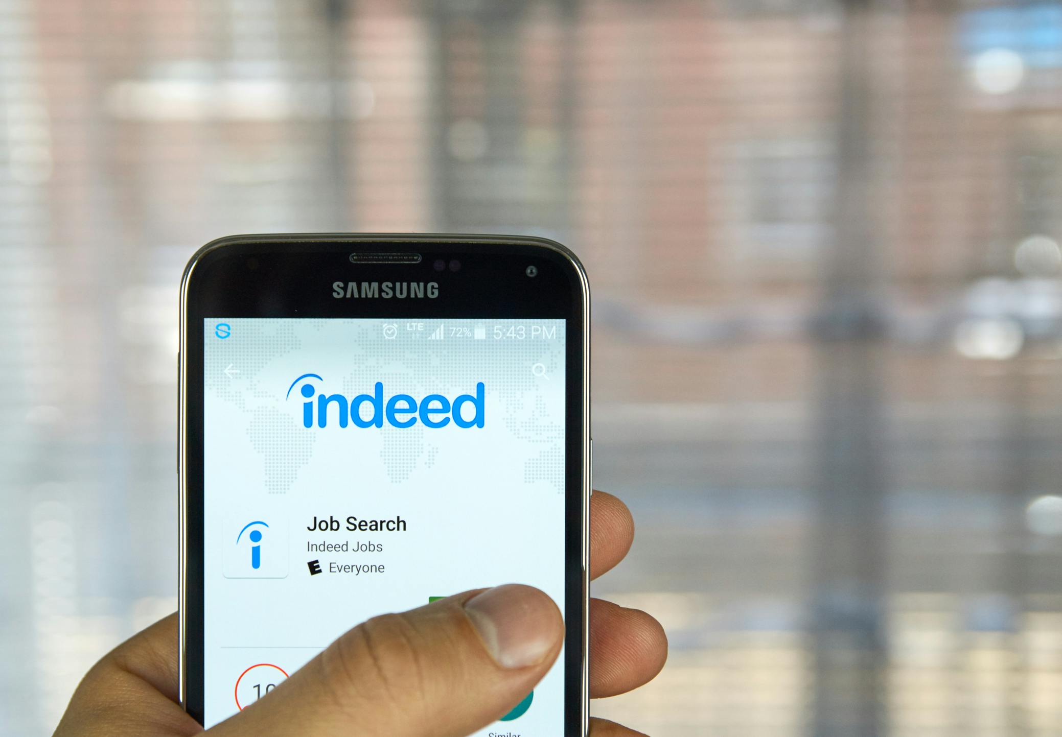 hand holds phone with Indeed app on screen set to find a job