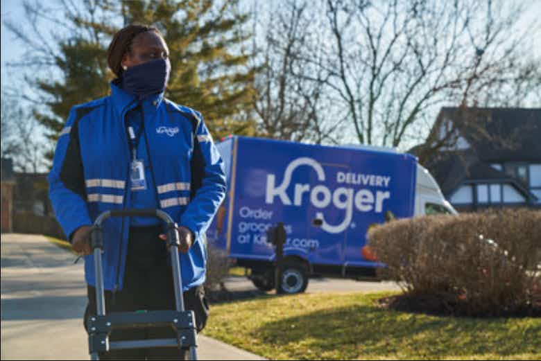 Kroger grocery delivery worker pushing a dolly with the Kroger truck in the background