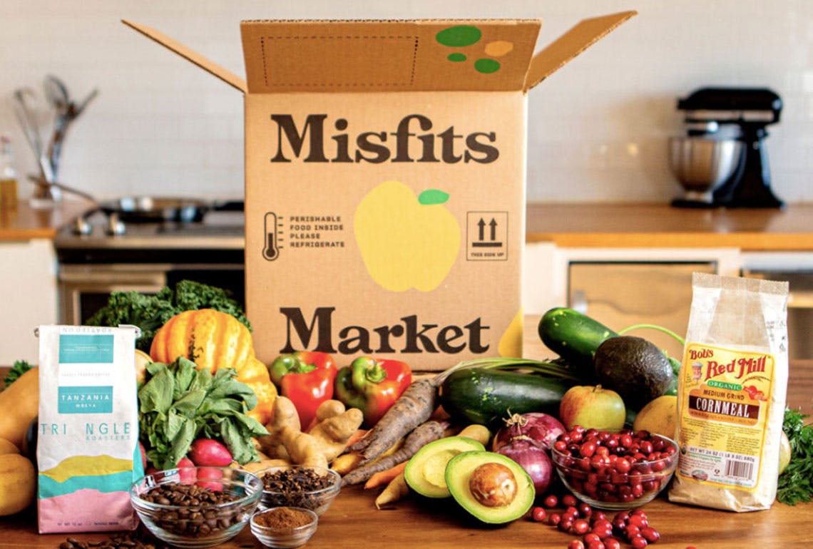 Box of Misfits Market produce on a kitchen counter with Bob's Red Mill, coffee, fruits, and veggies out of box.