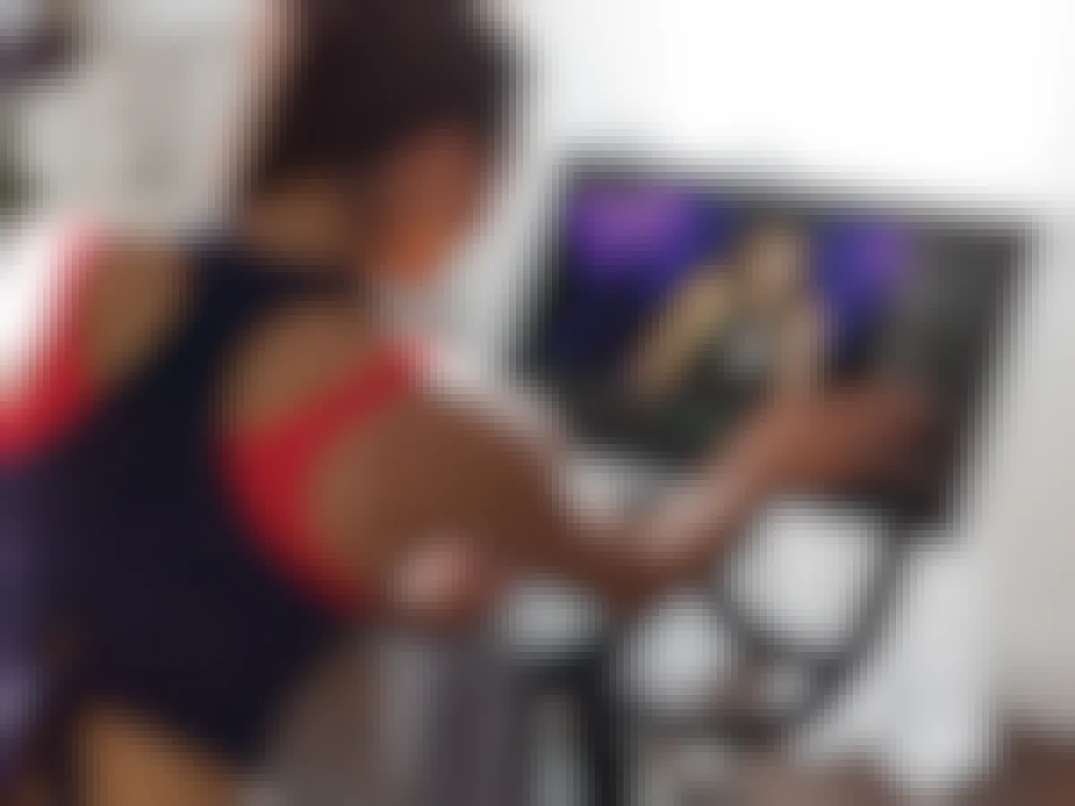 A person on a Peloton exercise bike using the touchscreen