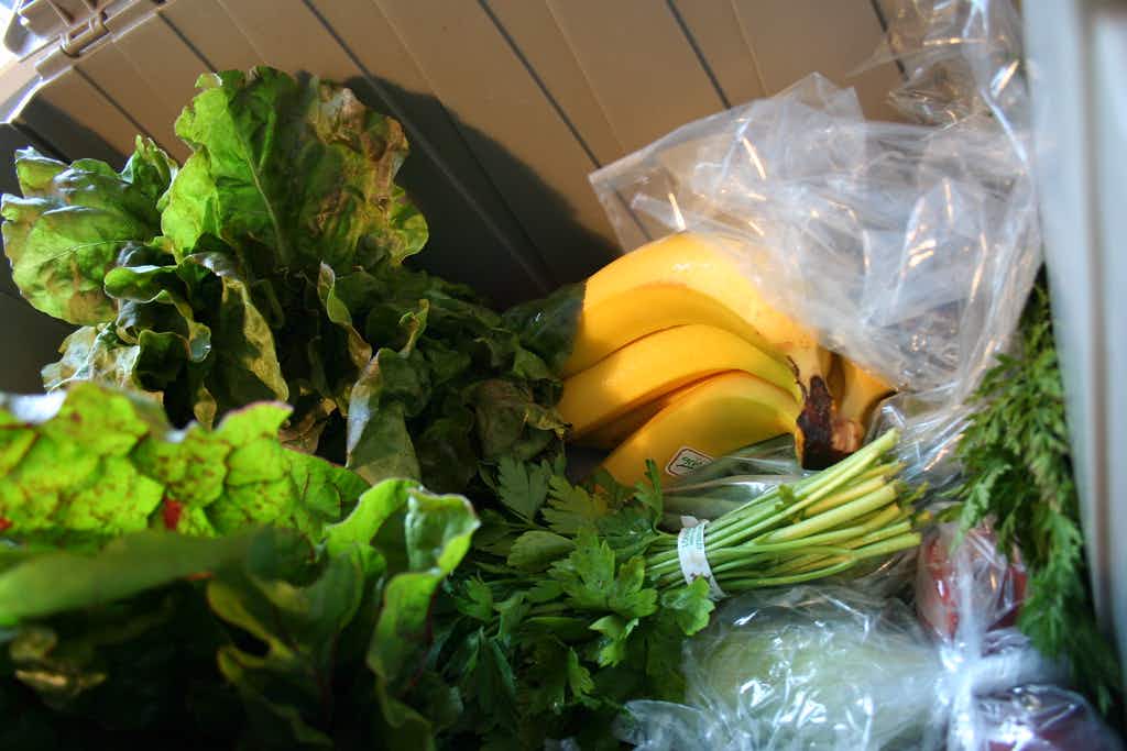 A delivered box of produce with lettuce, bananas, and other fresh vegetables.