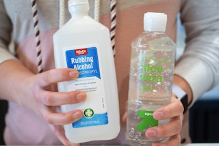 woman holding bottles of rubbing alcohol and aloe vera gel 