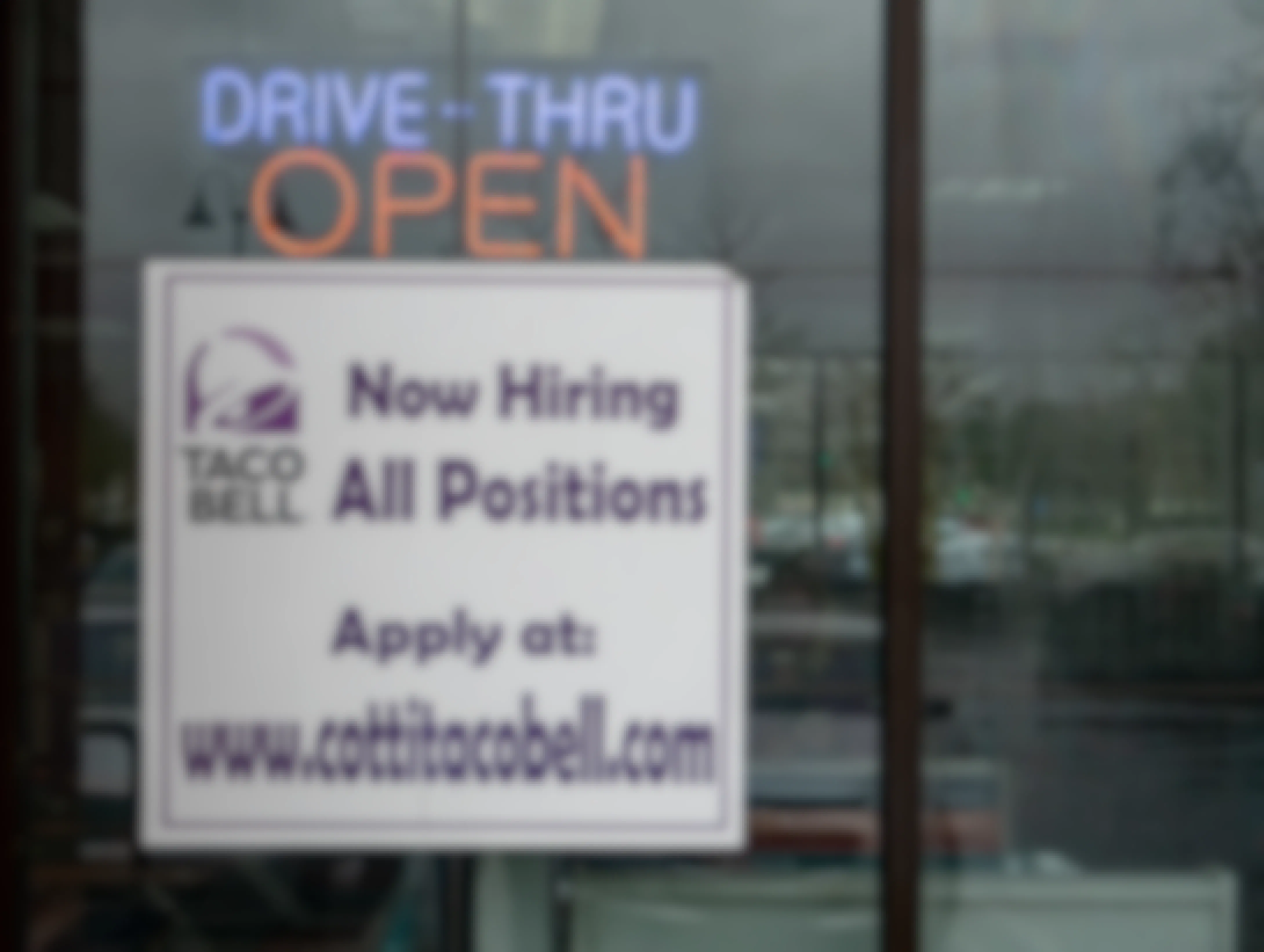 Outside of a Taco Bell with a sing reading "Now Hiring All Positions