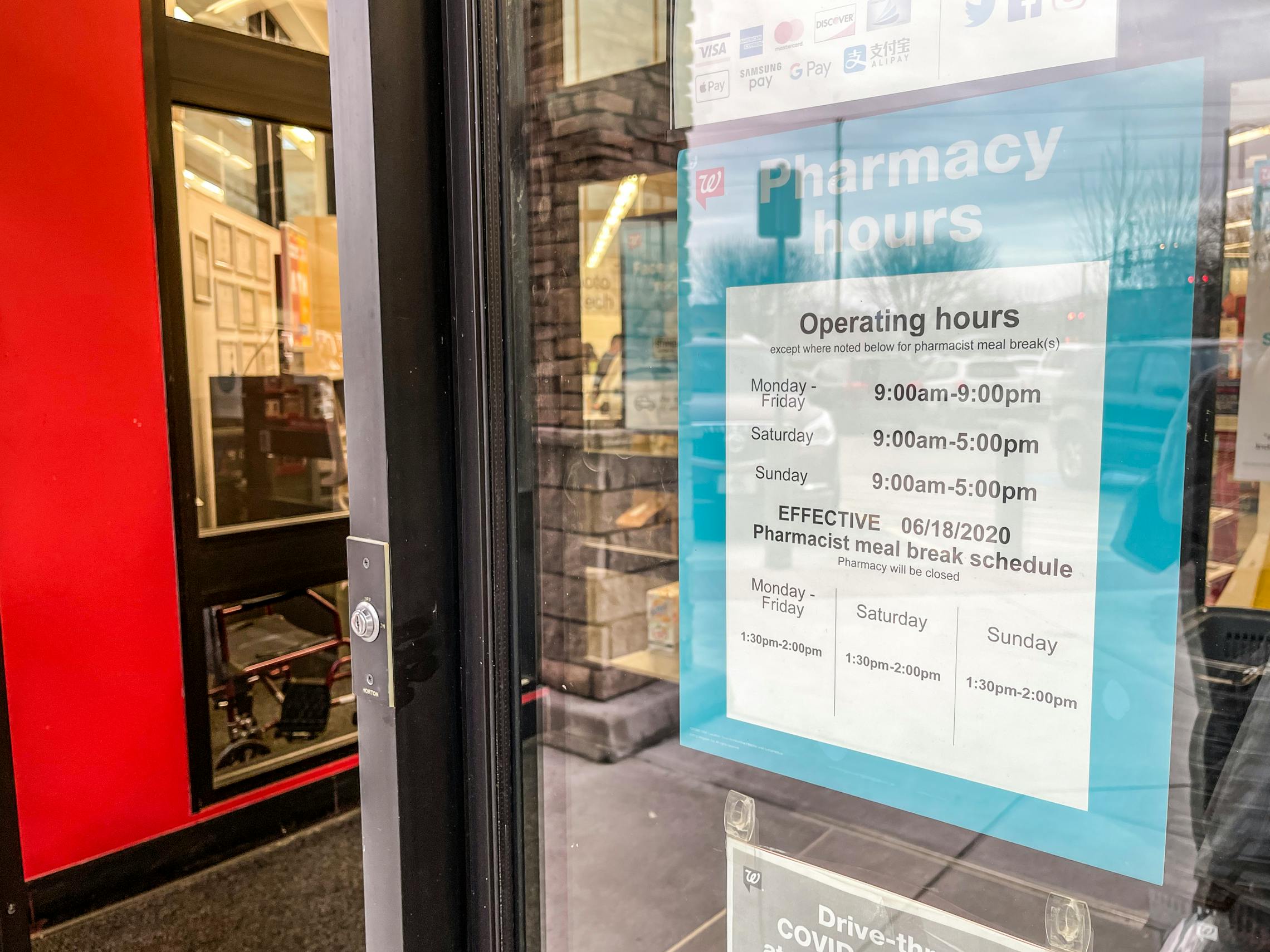 A sign with Walgreens store hours posted to the front door.