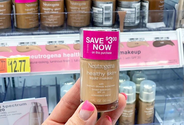 A person holds a bottle of liquid foundation with a coupon on it.