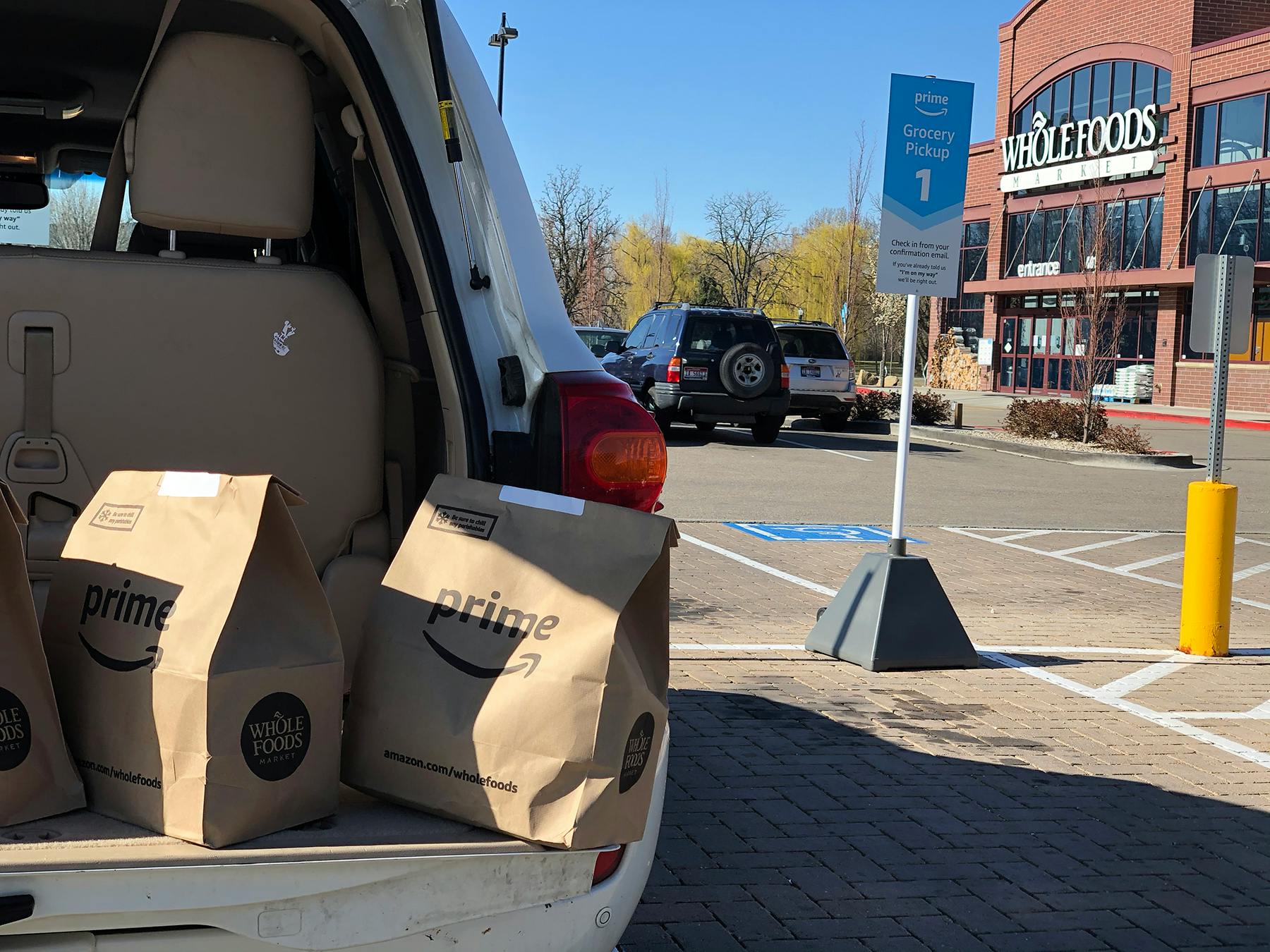 Brown grocery bags in the trunk of an SUV parked in front of Whole Foods.