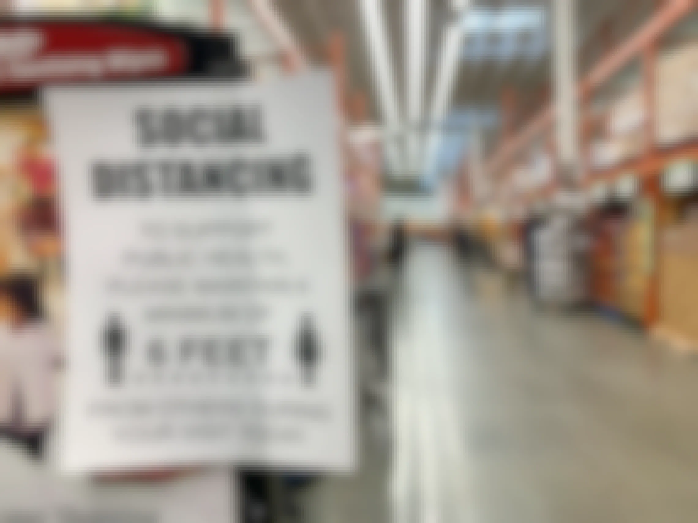 A sign posted inside a grocery store reminding people of "social distancing" as they shop.
