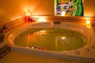 Nice atmosphere in bathroom with jacuzzi filled with water and bath salts, in the candle light.