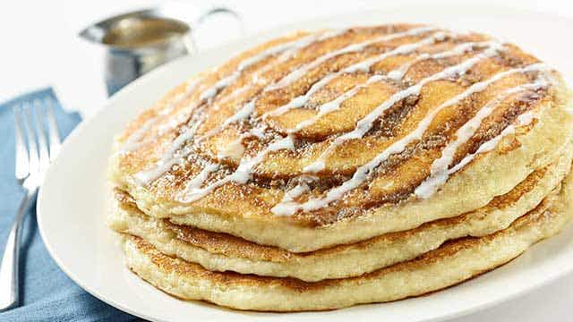 Cinnamon roll pancakes with icing on a plate.