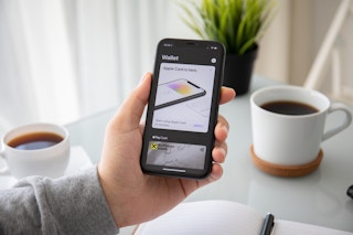 A person holding up a smartphone with Apple Wallet app pulled up