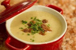 cheese soup in abowl with chives and bacon on top