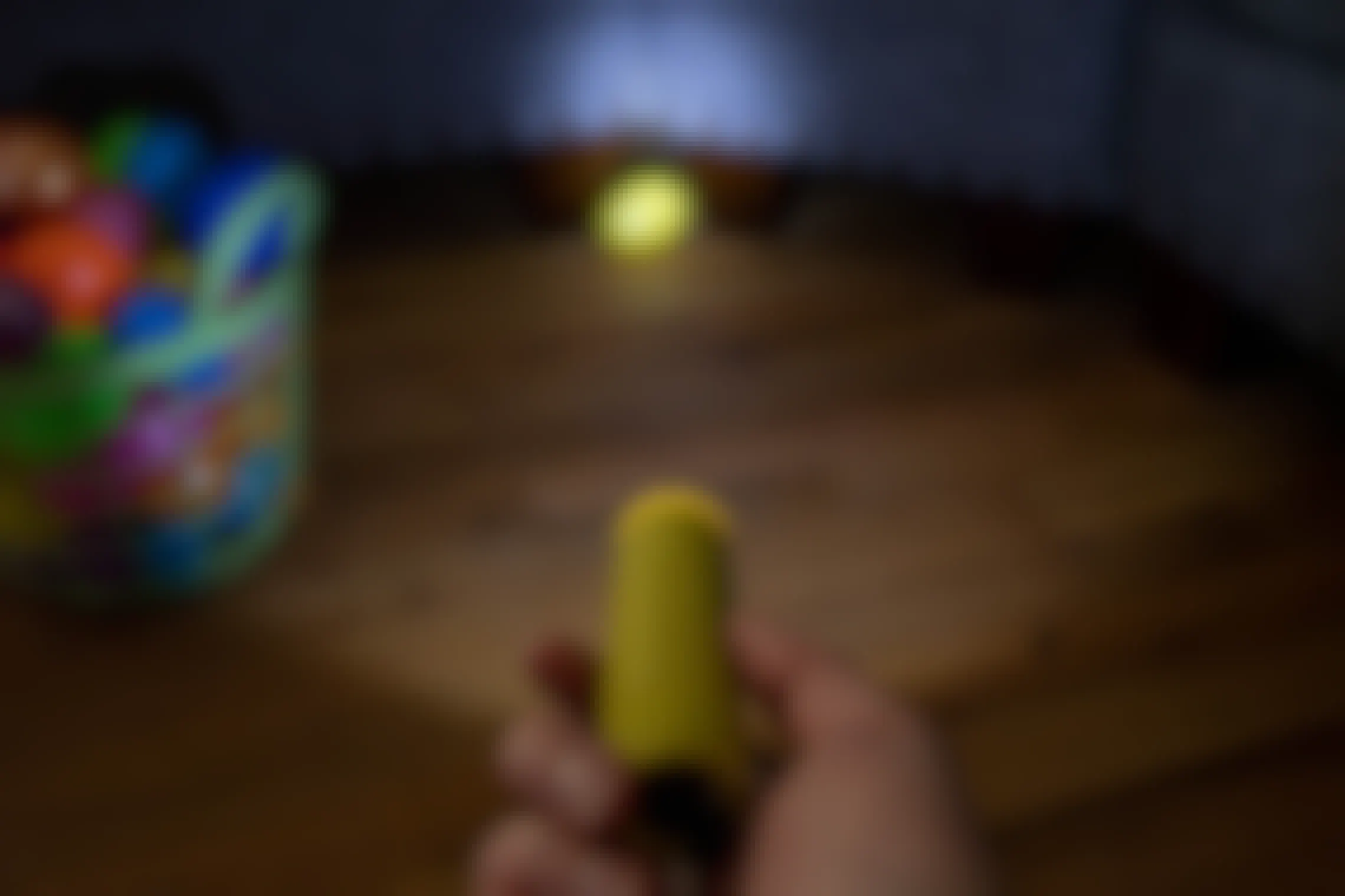 A flashlight pointed on a plastic easter egg with a basket of plastic eggs next to it.