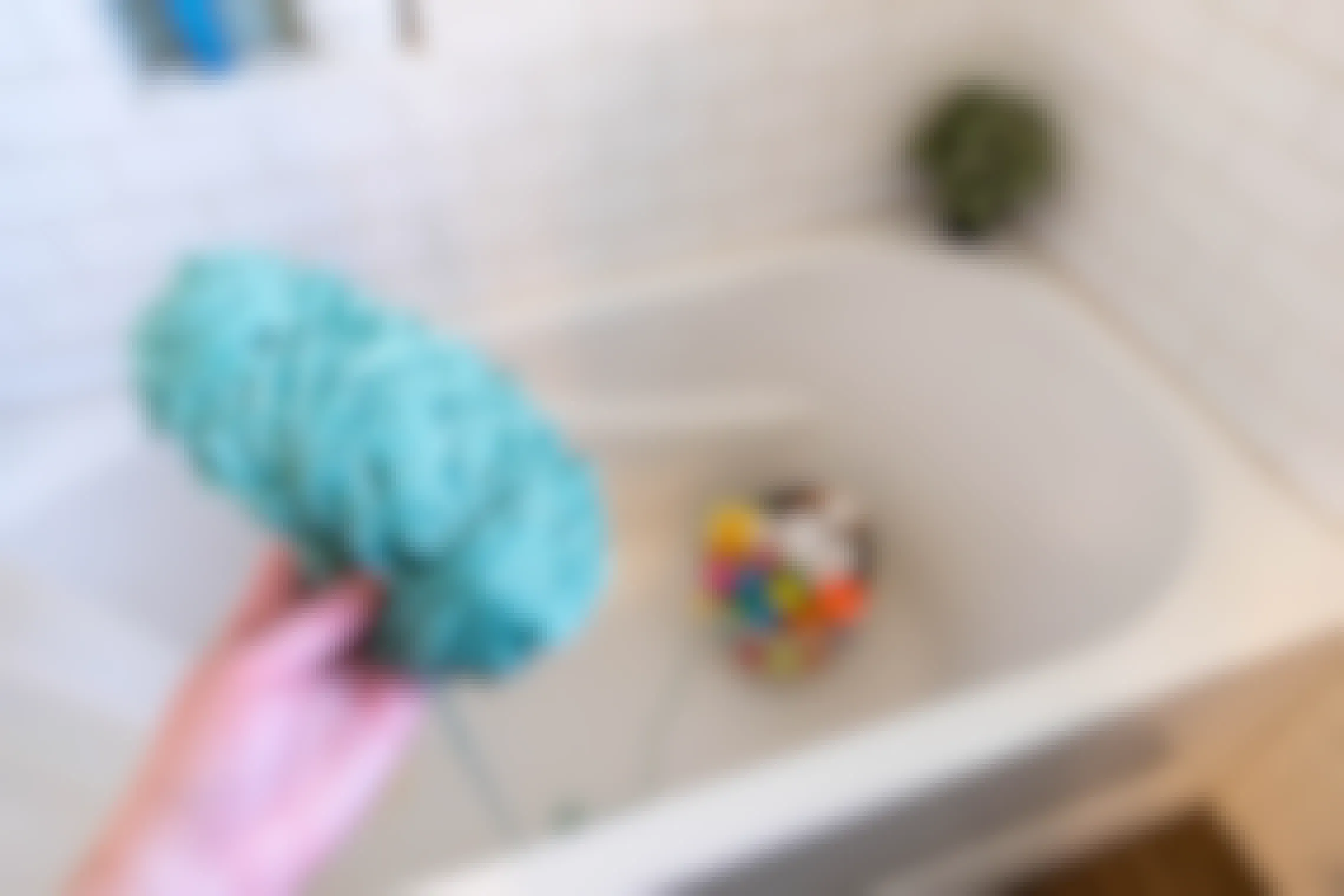 An Easter basket hidden in a bathtub with a string of yarn attached to it and the ball of yarn held in someones hand.