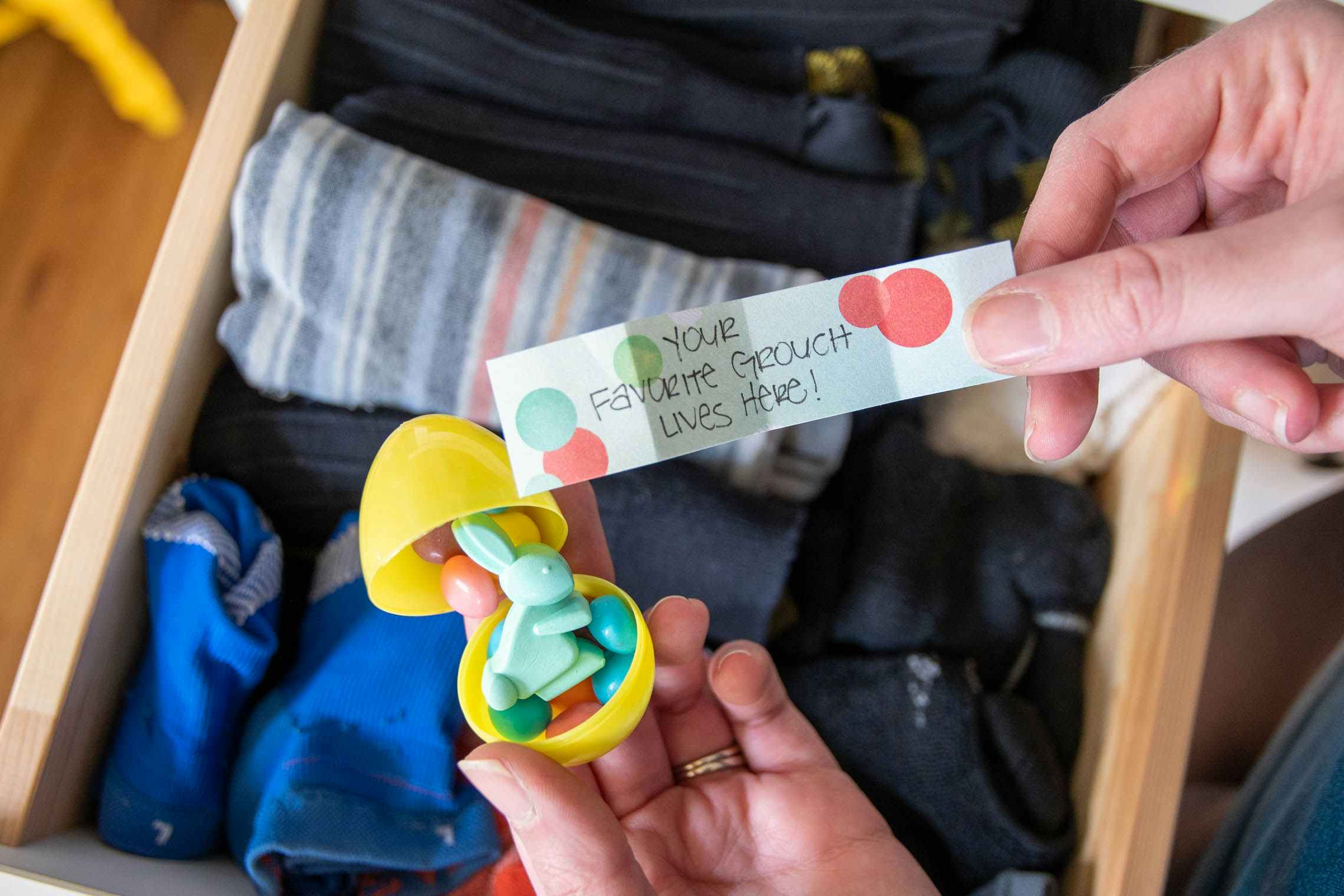 An plastic Easter egg held over a drawer filled with socks with a scavenger hunt clue in hand.