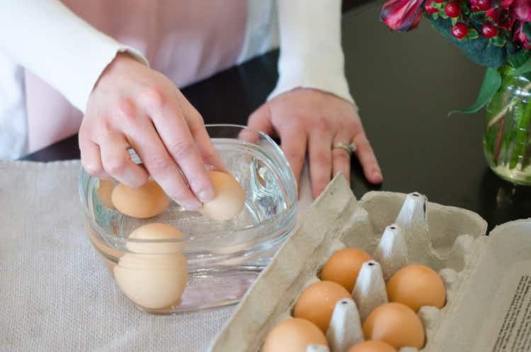 woman-placing-eggs-in-glass-bowl-with-warm-water-to-warm-up-the-eggs