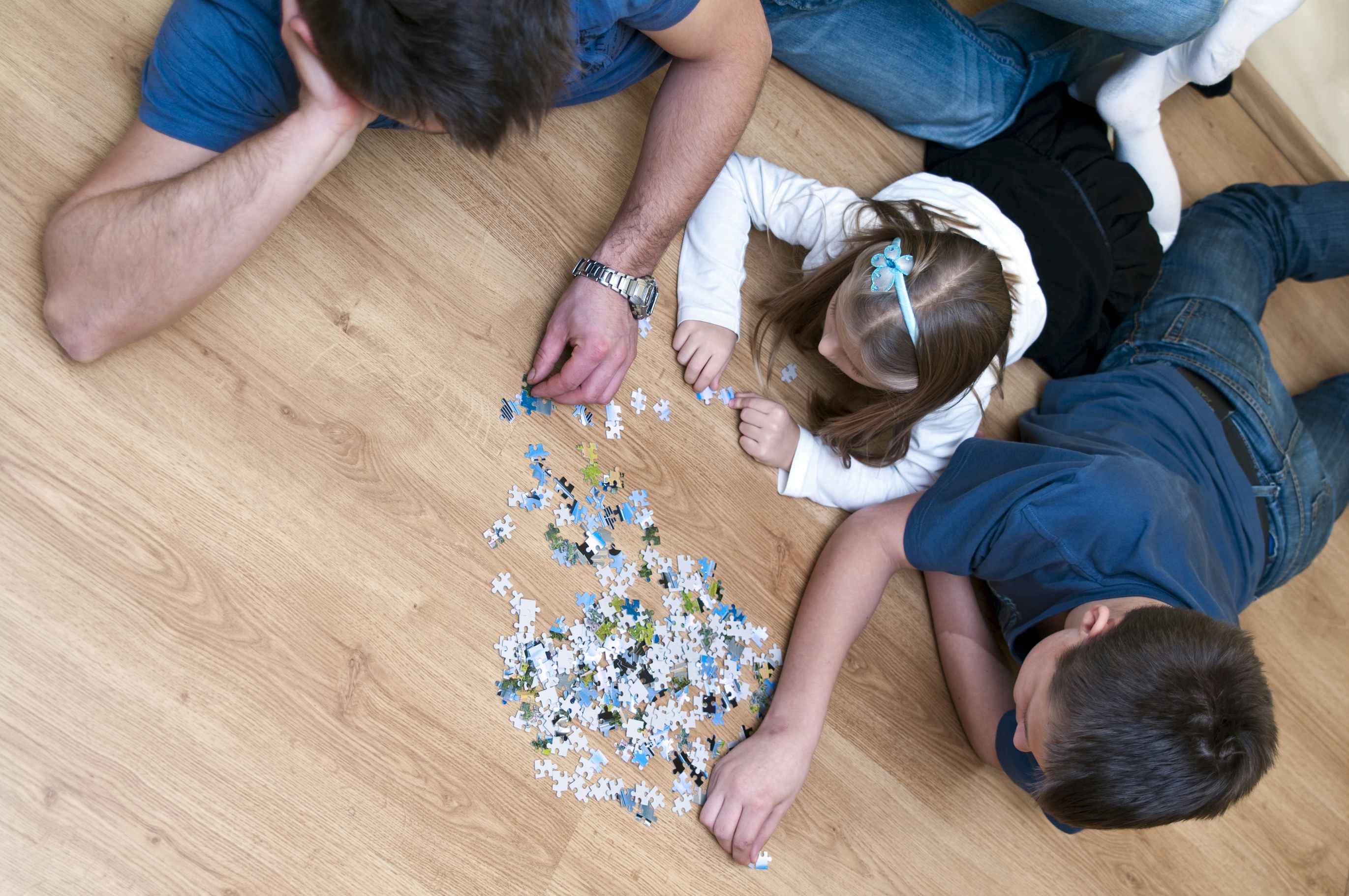 Family works on a puzzle together on the floor.