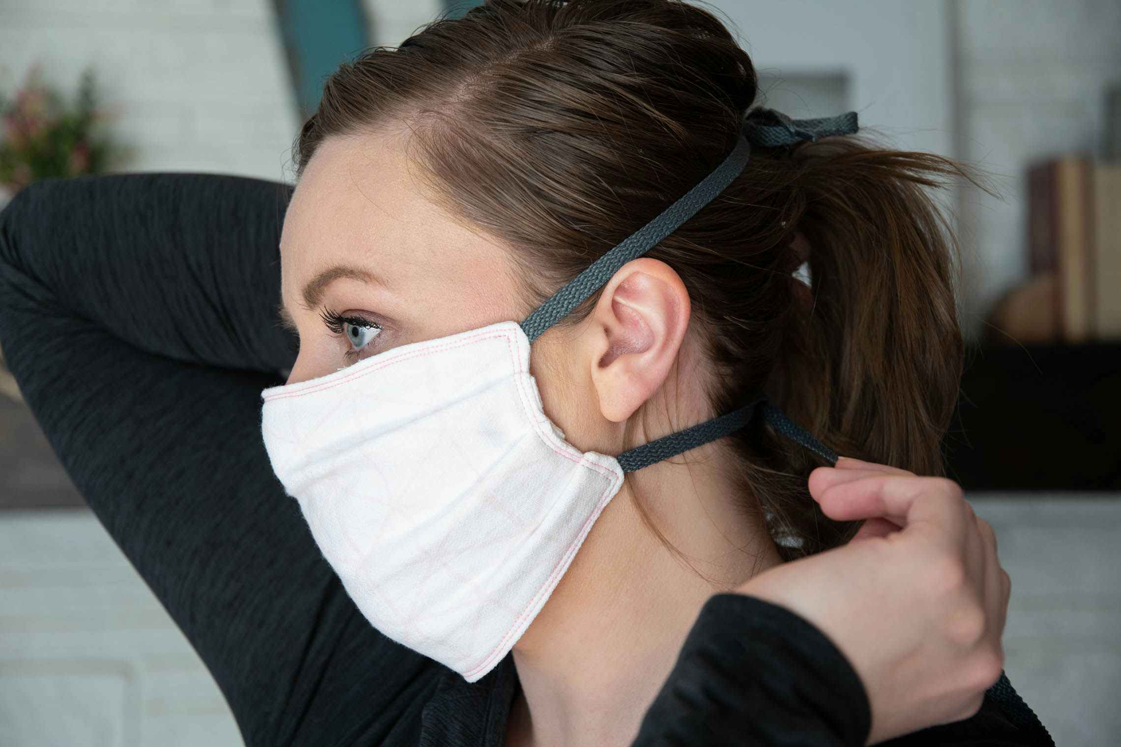 Woman attaching fabric mask to her face