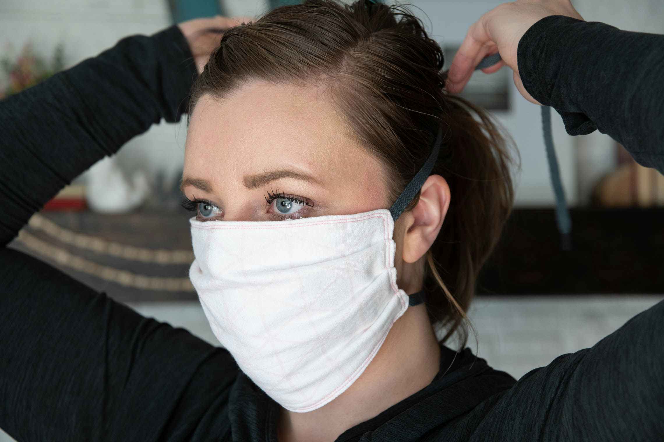 A woman trying on a fabric face mask.