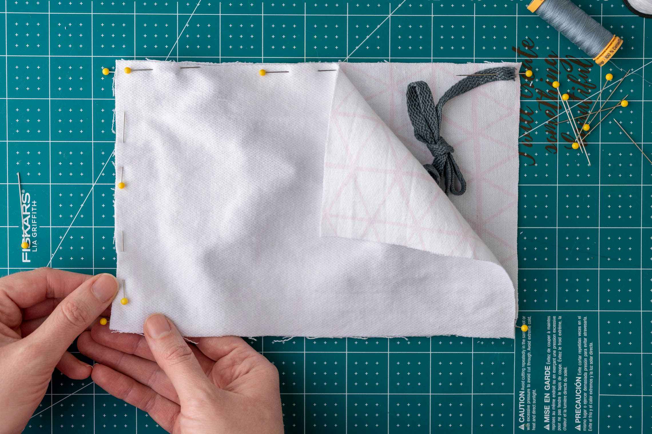 Placing the second piece of fabric on top of the first, covering the shoelaces, which are gathered in the middle.