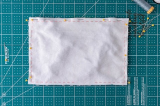 Fabric with red stitch marks showing 1/4" border to sew along the perimeter, leaving a hole at the bottom.