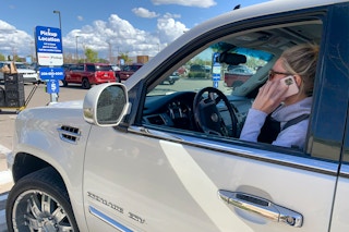 A woman on her phone sitting in a Fred Meyer grocery pickup spot.