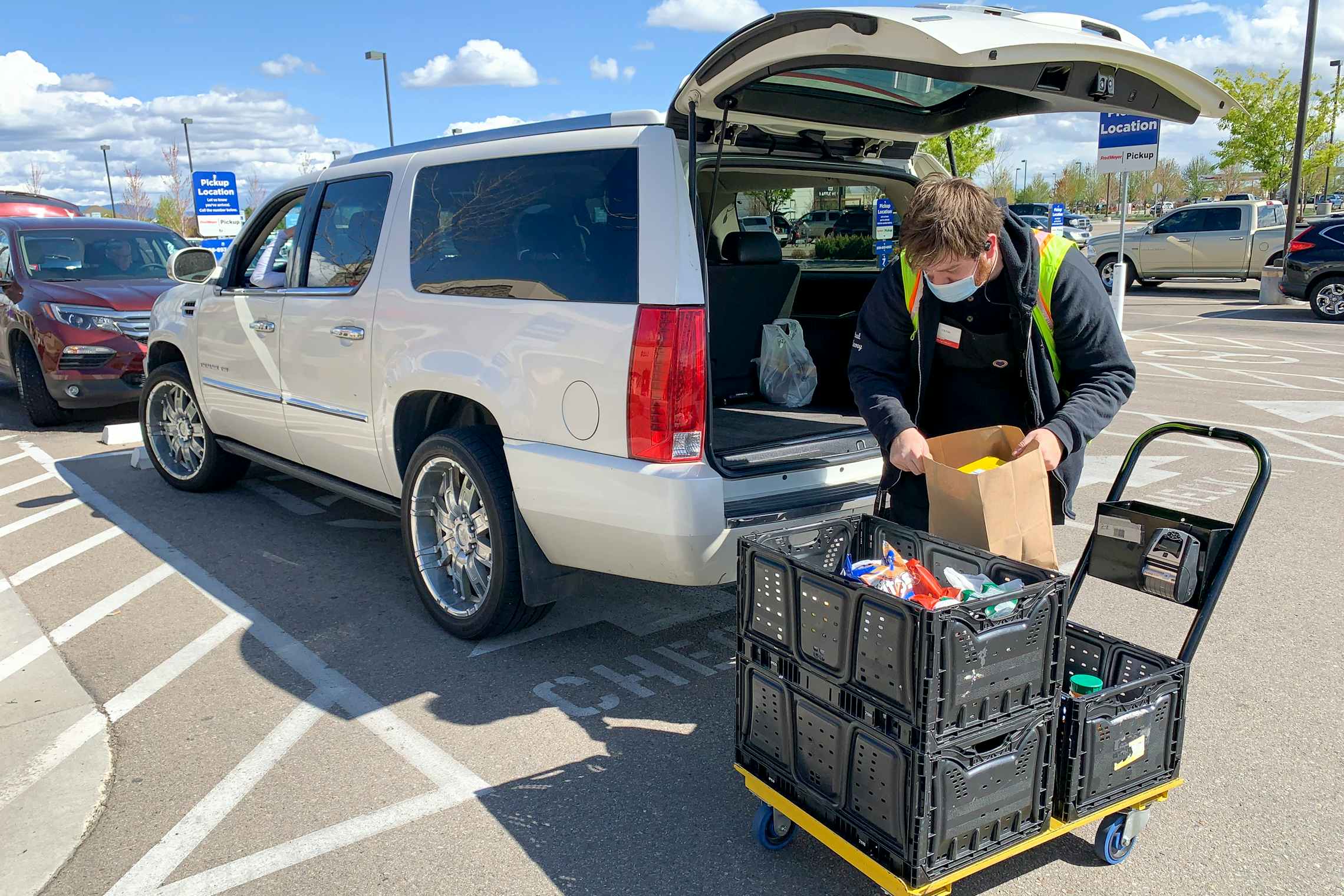 A Fred Meyer employee putting grocery items into the back of a vehicle.