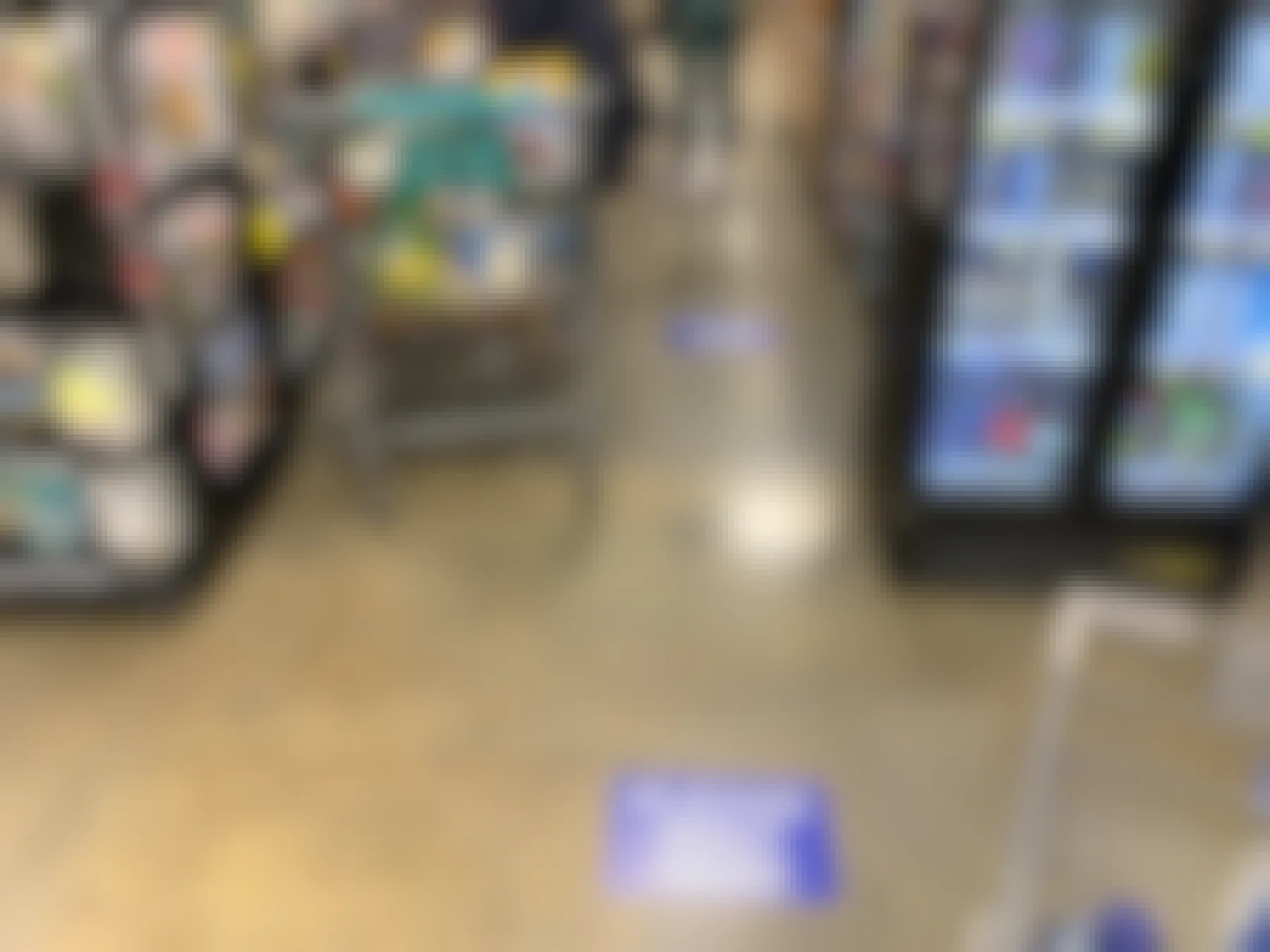A checkout line with people shopping, standing near markers on the floor that say, "Please Wait here