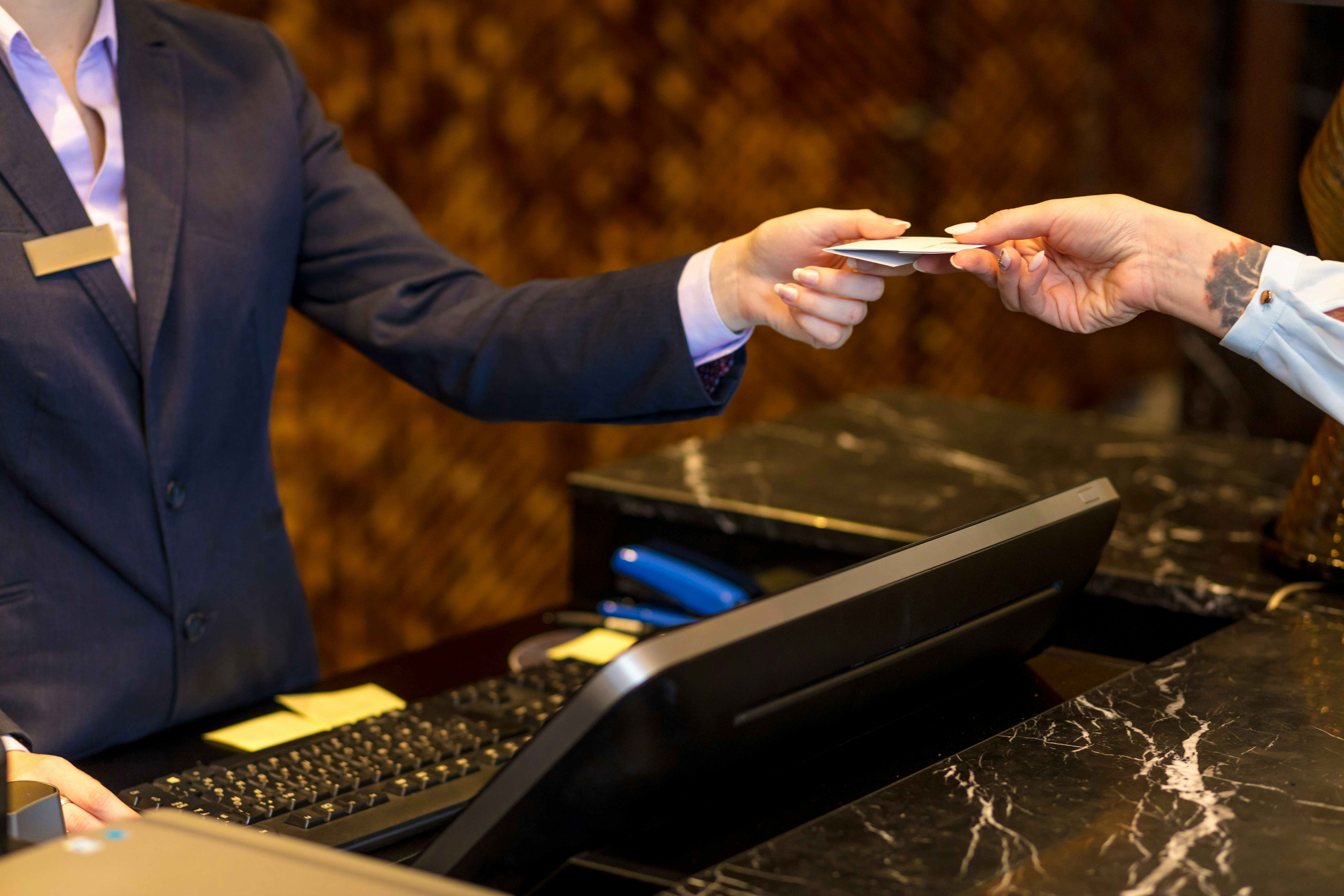 A person being handed a hotel room key at the check-in desk