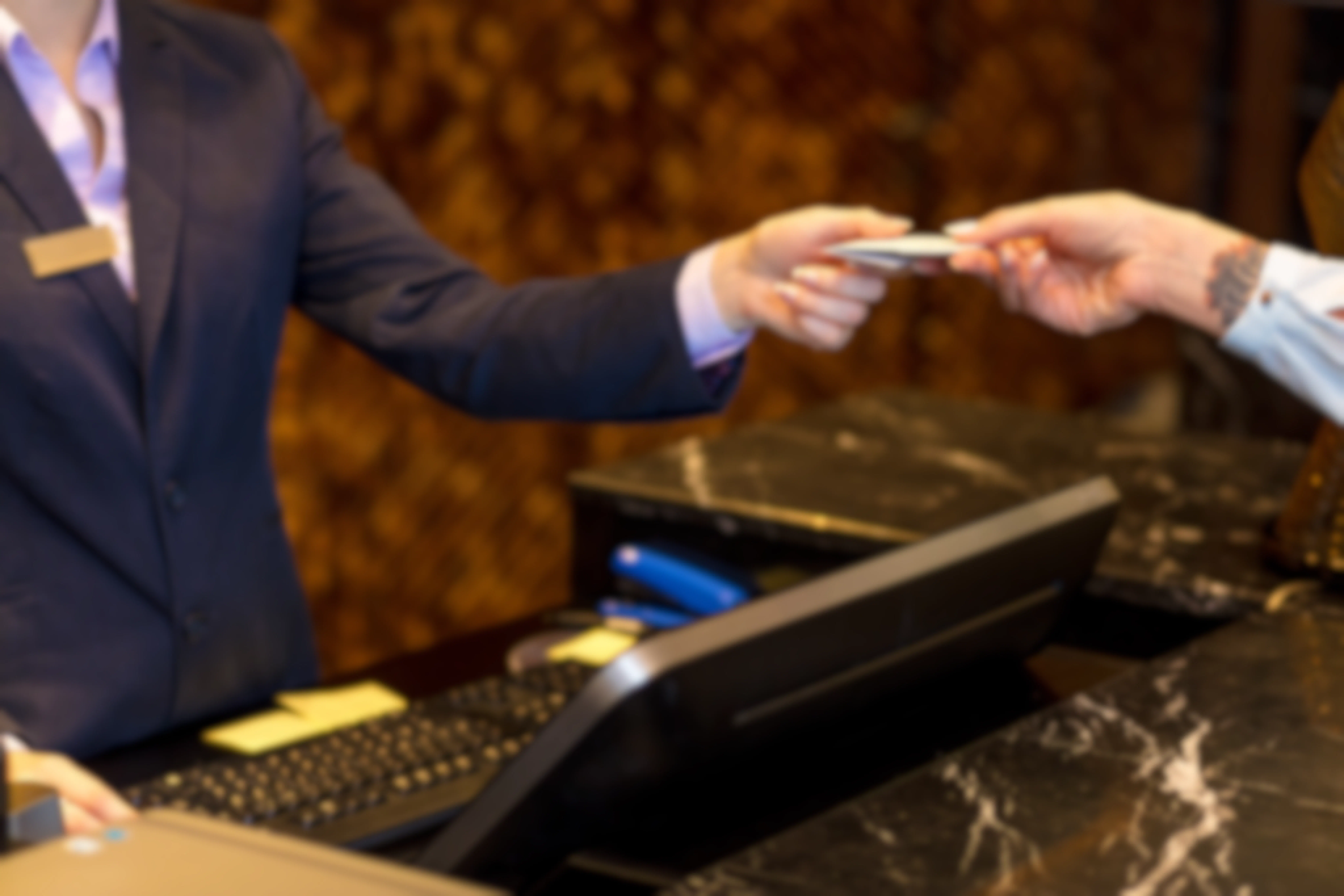 A person being handed a hotel room key at the check-in desk
