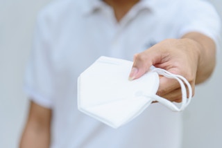 Man with N95 face mask in his hand, extended outward