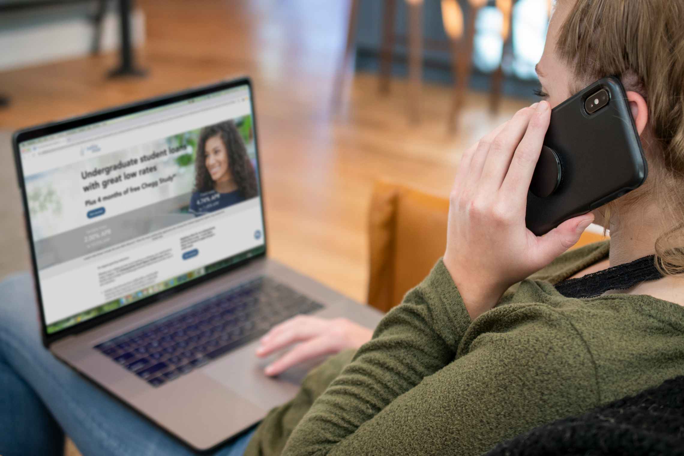 A woman on the phone with a computer open in front of her.